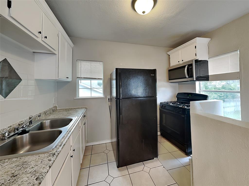 2911 Ryan Avenue Fort Worth, TX 76110 - Photo 19 of 27 a kitchen with granite countertop a refrigerator and a sink