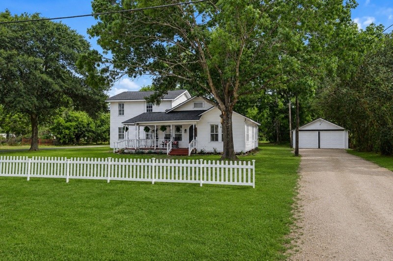 31730 Waller Tomball Road Waller, TX 77484 - Photo 2 of 50 Charming two-story home with a classic front porch, nestled behind a white picket fence. Surrounded by mature trees.