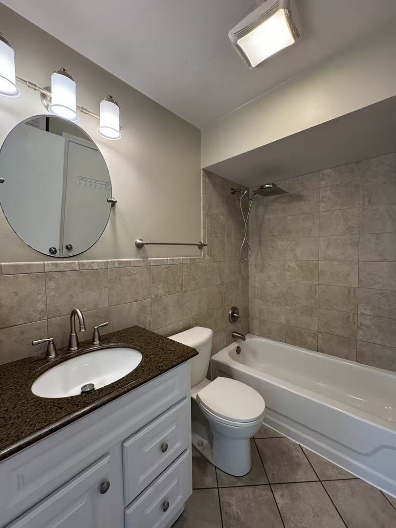 1326 Inverrary Lane, Unit 1326 Deerfield, IL 60015 - Photo 13 of 15 a bathroom with a granite countertop sink a toilet a mirror and bathtub