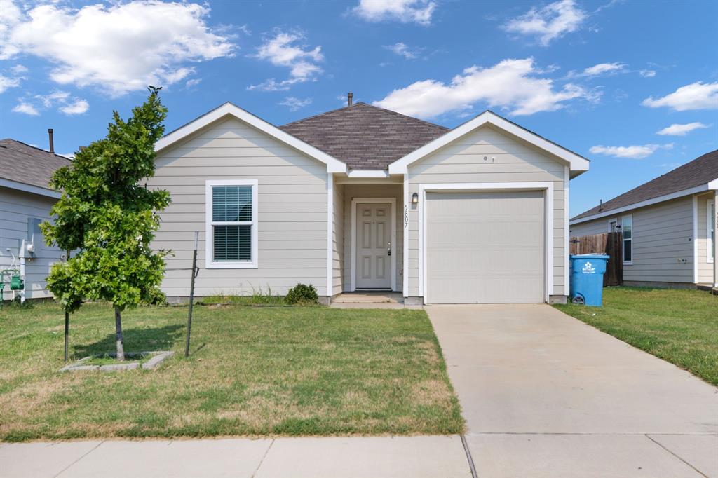 Ranch-style home with driveway, a front lawn, an attached garage, and roof with shingles
