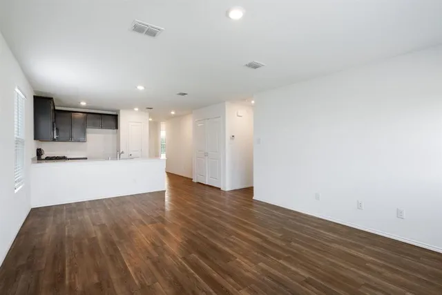 a view of an empty room with wooden floor and a sink