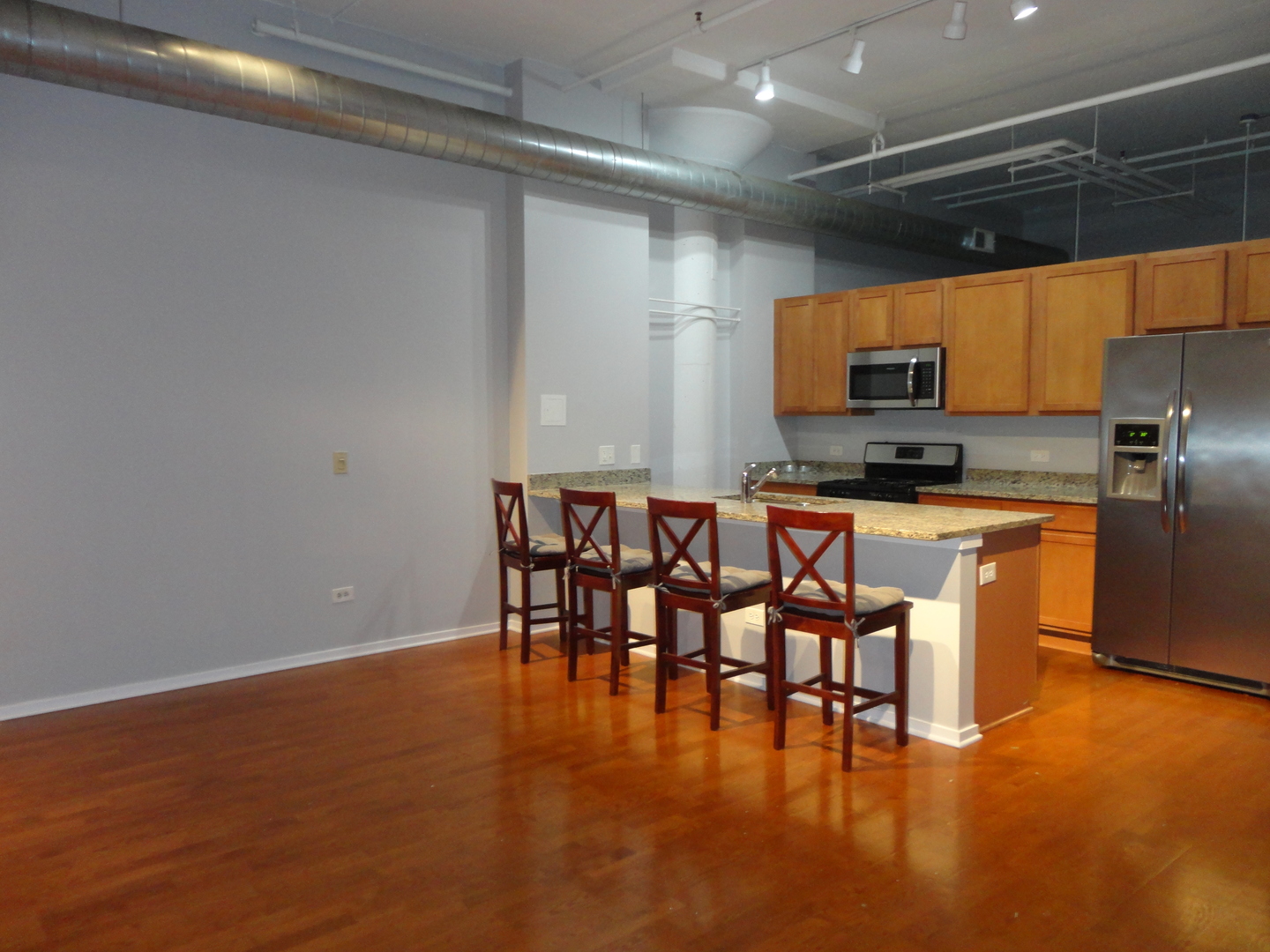 2323 West Pershing Road, Unit 136 Chicago, IL 60609 - Photo 8 of 20 a kitchen with stainless steel appliances granite countertop a stove top oven a sink a dining table and chairs with wooden floor
