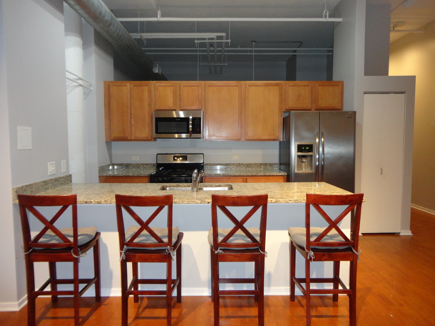 2323 West Pershing Road, Unit 136 Chicago, IL 60609 - Photo 10 of 20 a kitchen with stainless steel appliances kitchen island granite countertop a table chairs in it and wooden floor
