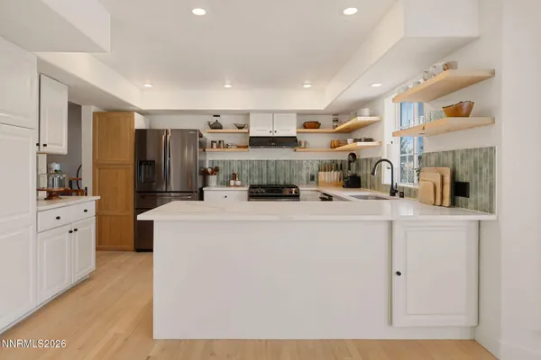 a kitchen with stainless steel appliances white cabinets and wooden floor