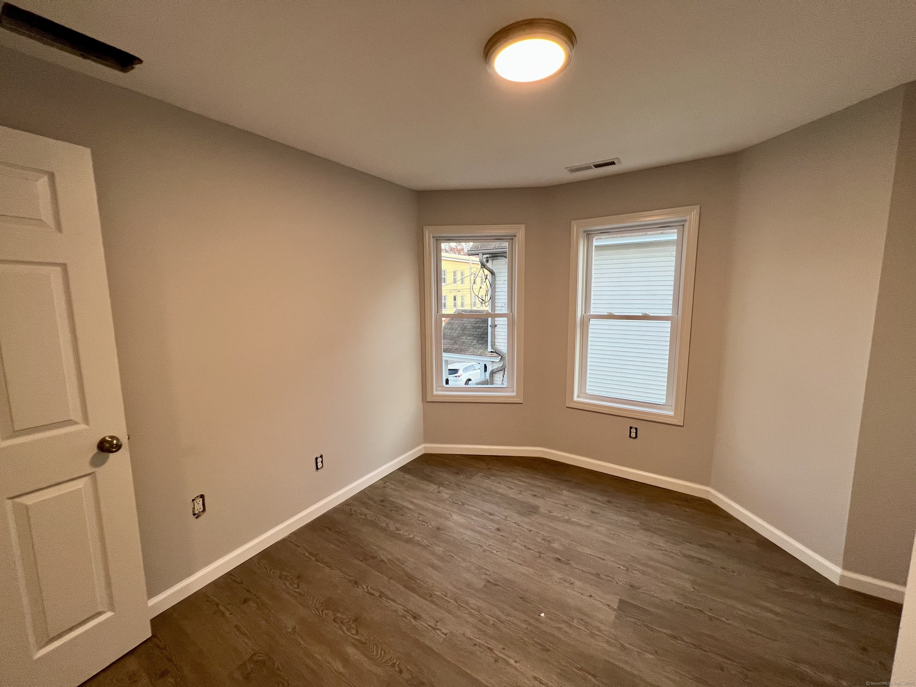 415 Hollister Avenue Bridgeport, CT 06607 - Photo 7 of 14 an empty room with wooden floor and windows