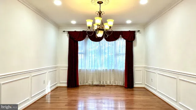 a view of a hallway with wooden floor and a chandelier