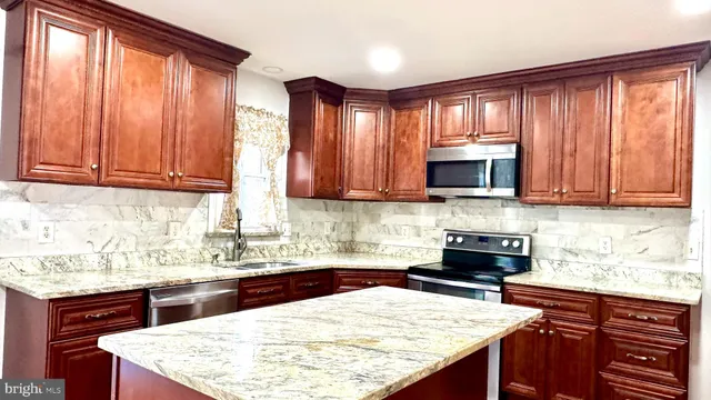 a kitchen with stainless steel appliances granite countertop a stove top oven a refrigerator and cabinets