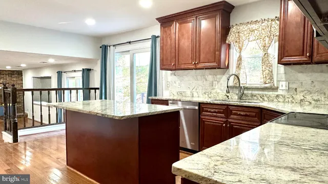 a kitchen with granite countertop wooden cabinets a stove top oven a sink and dishwasher