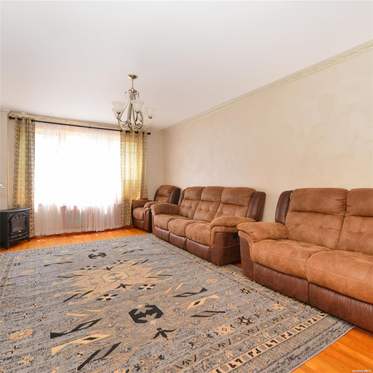 99-15 66th Avenue, Unit 4C Queens, NY 11374 - Photo 4 of 15 a living room with a couch and a chandelier