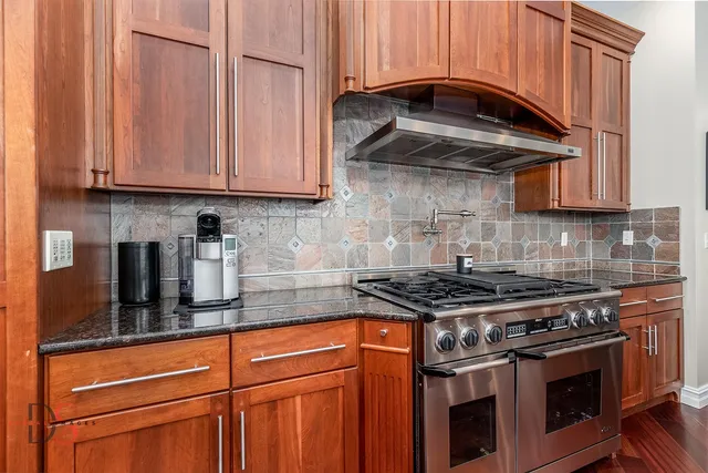 a kitchen with stainless steel appliances granite countertop wooden cabinets a stove and a sink