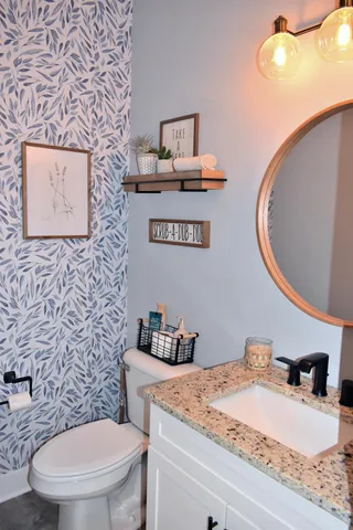 a bathroom with a granite countertop toilet sink and mirror