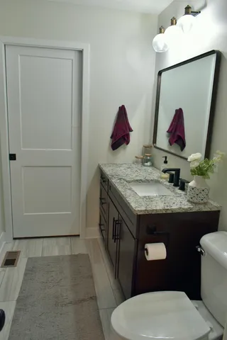 a bathroom with a granite countertop toilet sink and mirror
