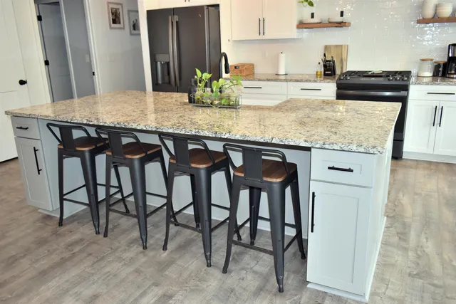 a kitchen with stainless steel appliances granite countertop table chairs sink and stove