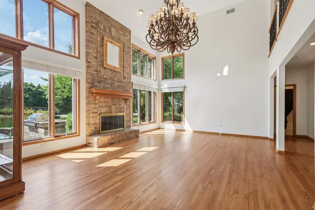 a view of an empty room with wooden floor and a fireplace