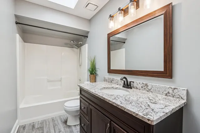 a bathroom with a granite countertop sink a mirror and a shower