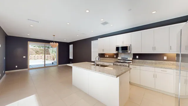 a large hall with stainless steel appliances granite countertop a sink and cabinets