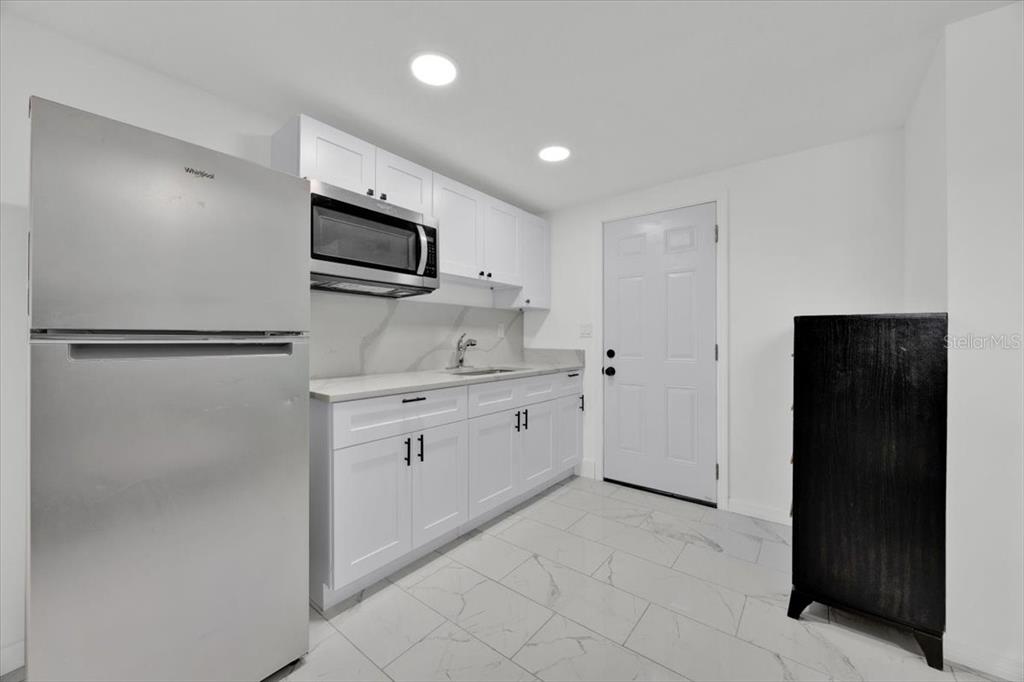 2930 Rio Lane Orlando, FL 32805 - Photo 24 of 28 a kitchen with granite countertop white cabinets and refrigerator