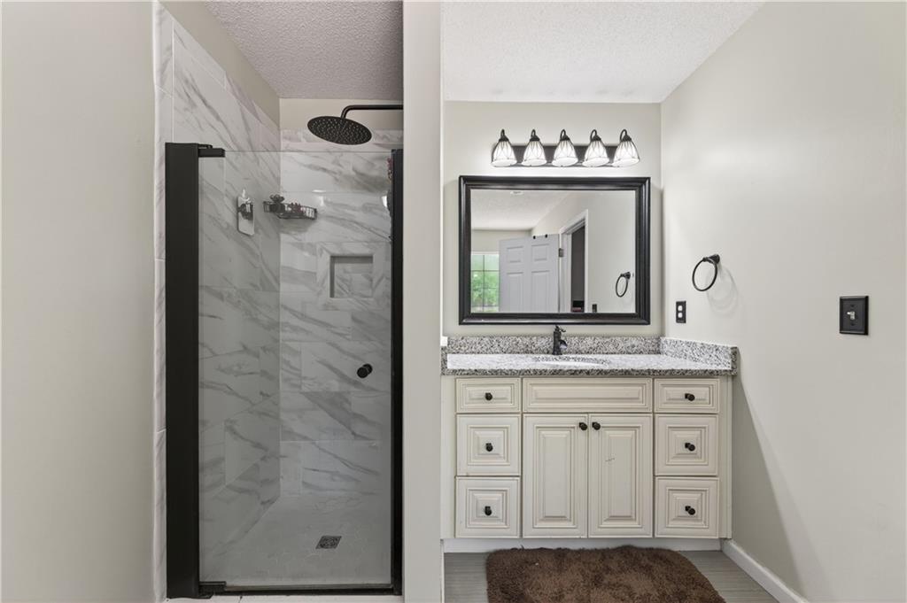 3904 Keystone Ridge Acworth, GA 30101 - Photo 22 of 45 a bathroom with a granite countertop sink a mirror and a shower