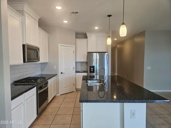a kitchen with kitchen island granite countertop a sink a counter space appliances and cabinets