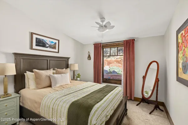 a bedroom with a bed and a large mirror next to a window