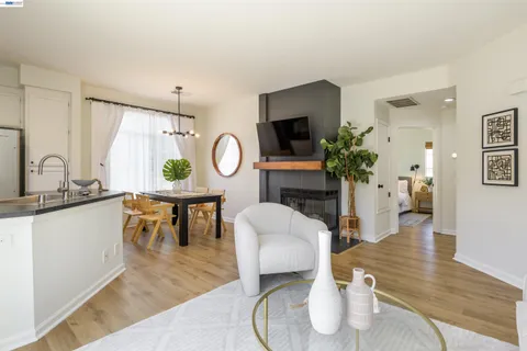 a living room with furniture a potted plant and open kitchen view