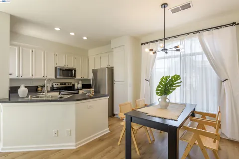 a kitchen with stainless steel appliances a dining table chairs a refrigerator and a counter space