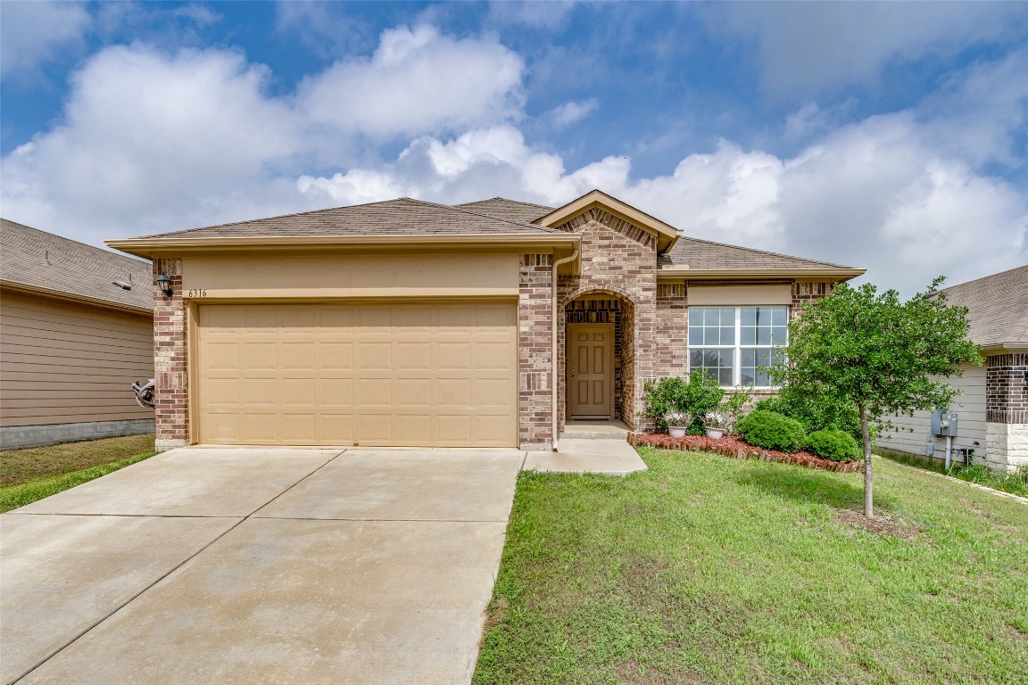 View of front of property with a front yard, brick siding, concrete driveway, an attached garage, and roof with shingles