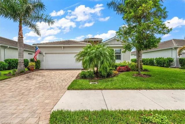 a front view of a house with a garden and palm trees