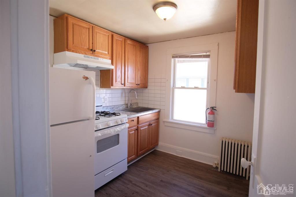 417 Chestnut Street, Unit B Middlesex, NJ 08846 - Photo 9 of 12 a kitchen with wooden cabinets and a stove top oven