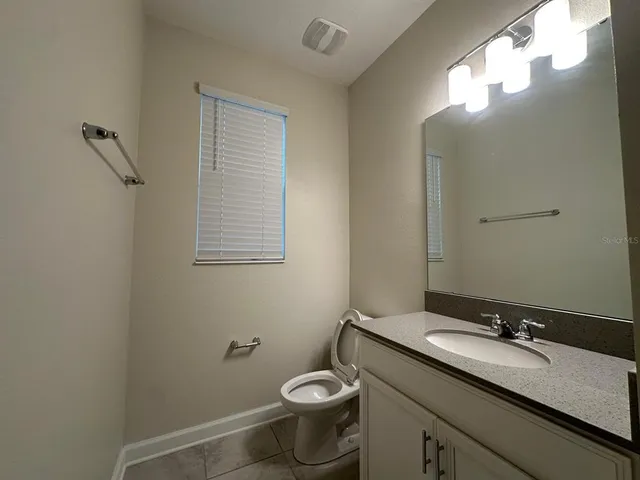 a bathroom with a granite countertop toilet sink and mirror