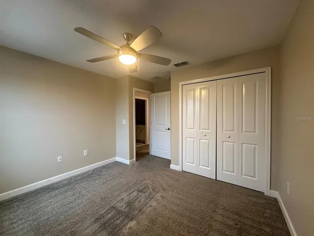 a view of an empty room and chandelier fan