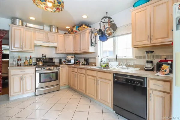 a kitchen with stainless steel appliances granite countertop a stove top oven a sink a dining table and chairs
