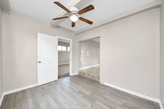 an empty room with wooden floor and ceiling fan