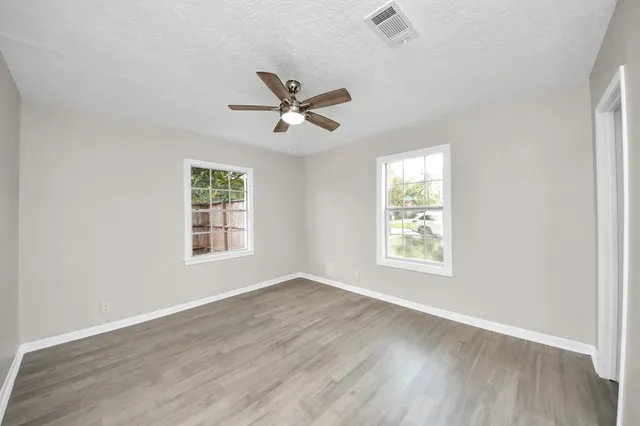 a view of an empty room with a window and wooden floor
