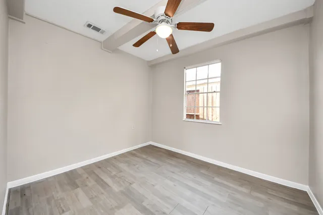 an empty room with a window and a fan