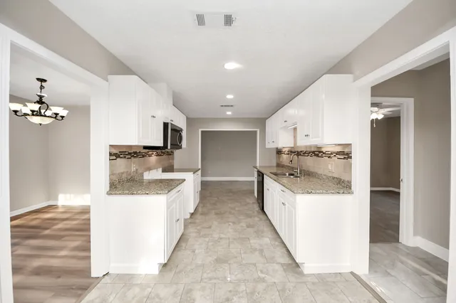a large white kitchen with a sink and refrigerator