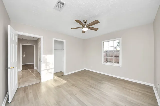 a view of empty room with wooden floor and fan