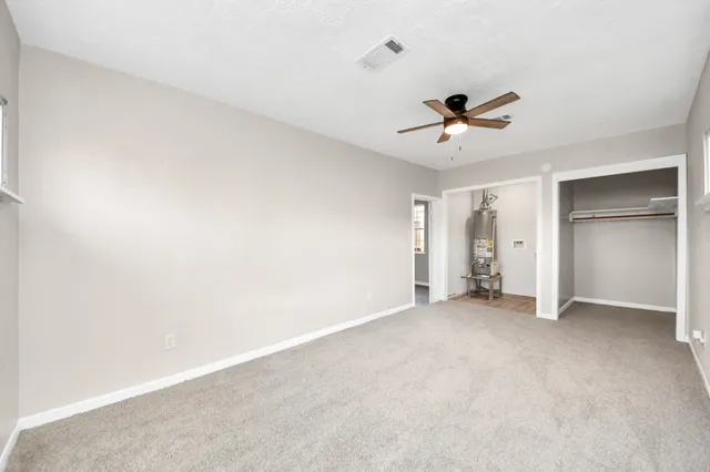 an empty room with closet and a ceiling fan