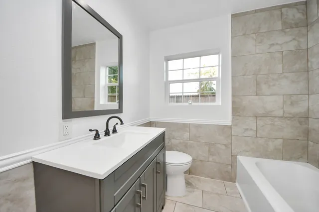a bathroom with a sink toilet a mirror and bathtub