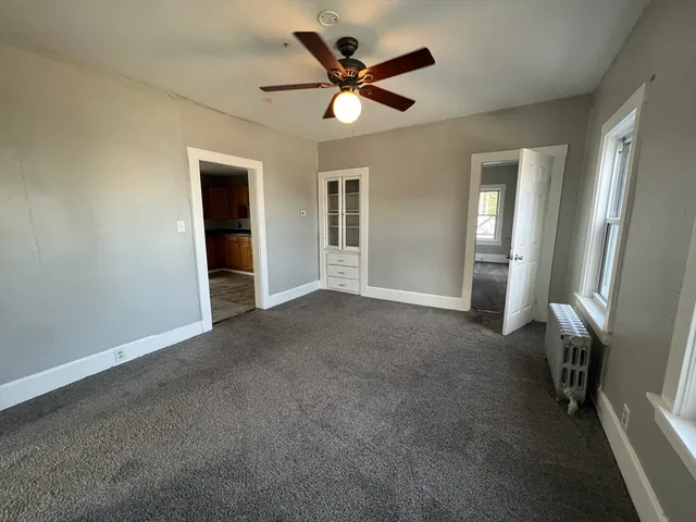 an empty room with ceiling fan and window