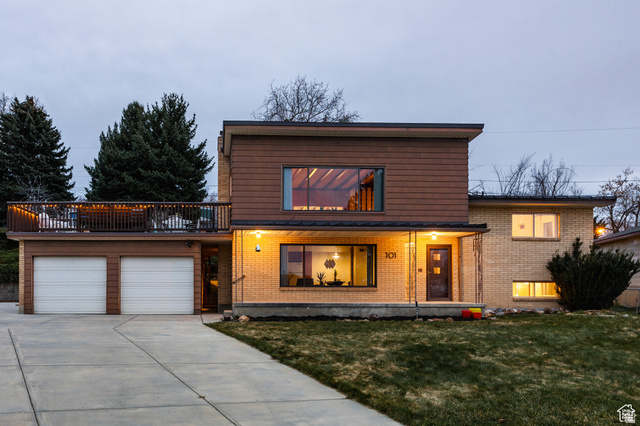 View of front of house with brick siding, a garage, driveway, and a front lawn