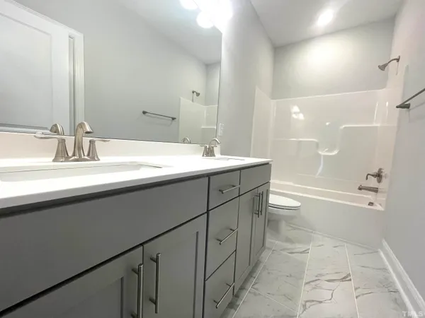a bathroom with a sink a toilet a mirror and shower