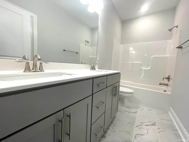 a bathroom with a sink a toilet a mirror and shower