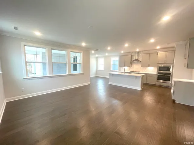 a view of a big room with wooden floor and windows