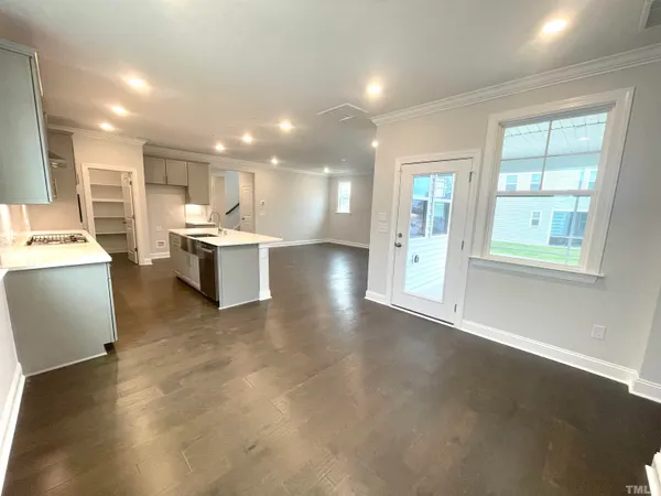 a view of a kitchen with kitchen island a sink wooden floor and a large window