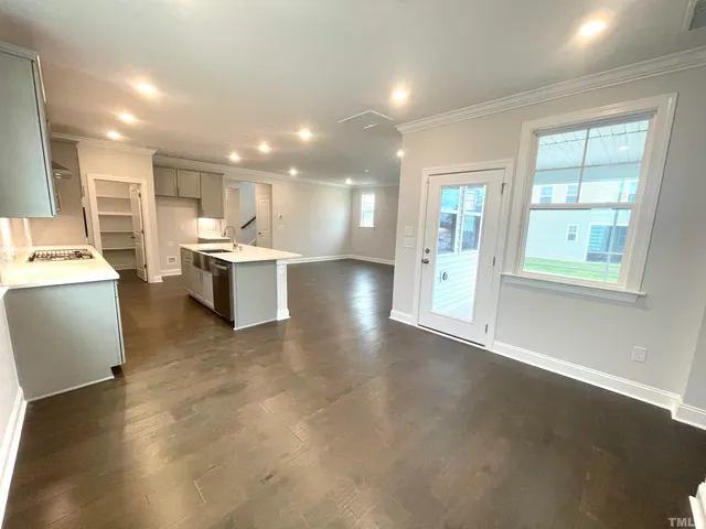 a view of a kitchen with kitchen island a sink wooden floor and a large window