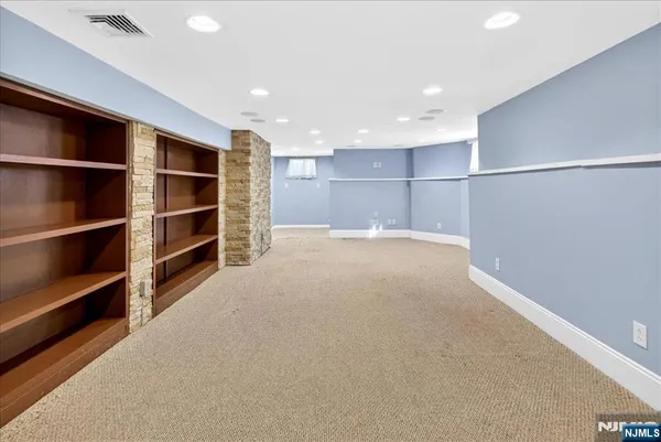 a view of an empty room with a cabinet and mirrors