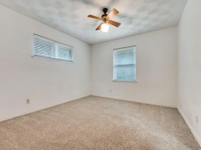 an empty room with a window and a ceiling fan