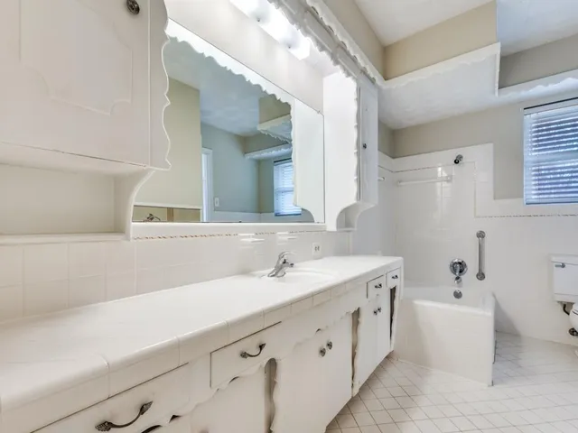 a bathroom with a double vanity sink mirror and bathtub