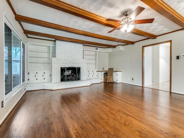 a view of empty room with wooden floor and fireplace
